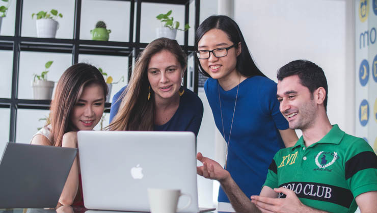 Group of co-workers huddled around a computer