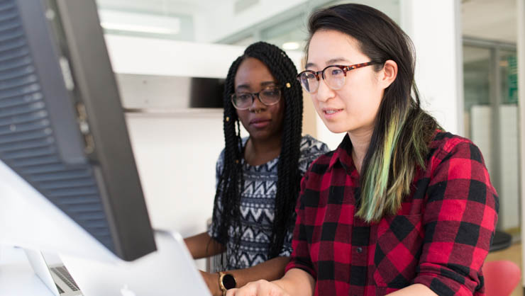 Two women working together on a computer