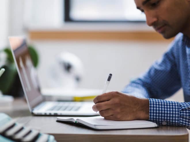 Man writing in a notebook at a desk