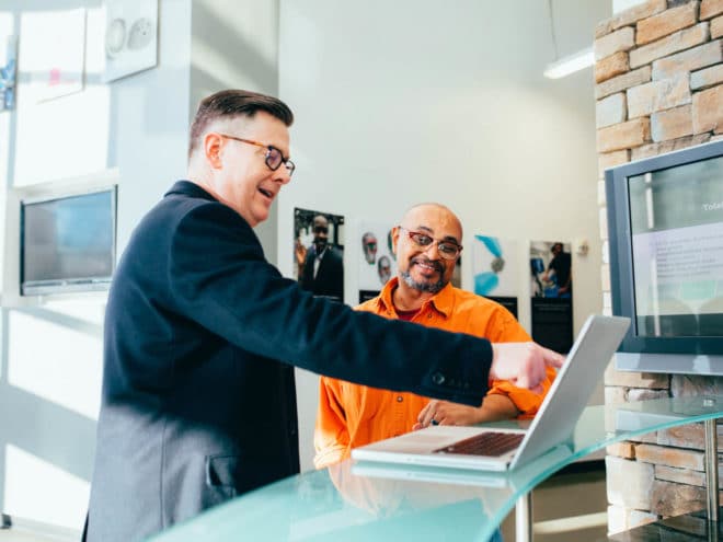 Man showing other man something by pointing at a computer screen