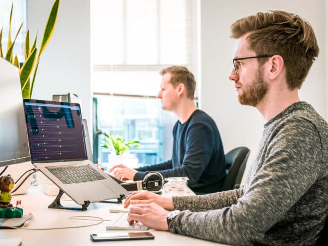 Two men working on computers at their desks