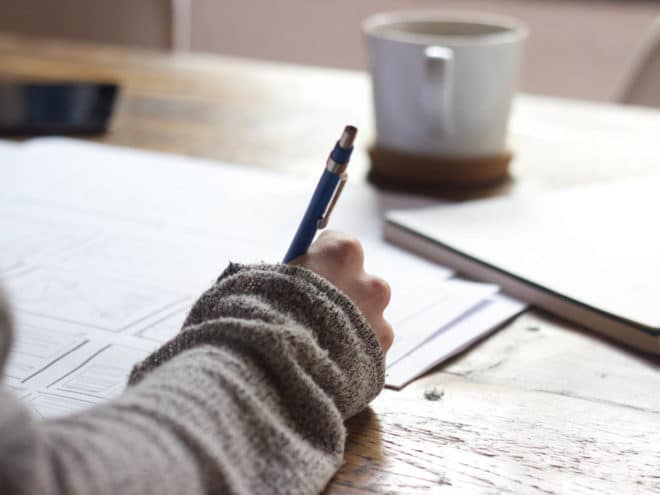 Person writing in a notebook at a desk